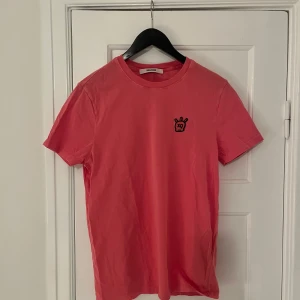 Rosa t-shirt från Zadig & Voltaire - Säljer en snygg rosa t-shirt från Zadig & Voltaire med ett coolt broderat motiv på bröstet. T-shirten är kortärmad och gjord i mjukt material för en bekväm passform. Perfekt för en avslappnad stil.