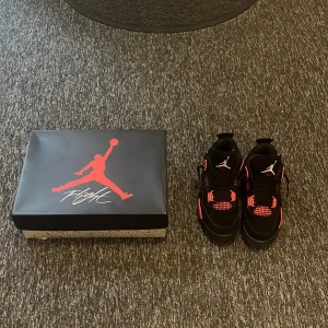 Svarta och röda Nike Air Jordans - Snygga Nike Air Jordans i svart och rött med klassisk Jumpman-logga. Skorna har snörning och en iögonfallande design med röda detaljer på sidorna och sulan. Perfekta för dig som vill ha en stilren och sportig look.