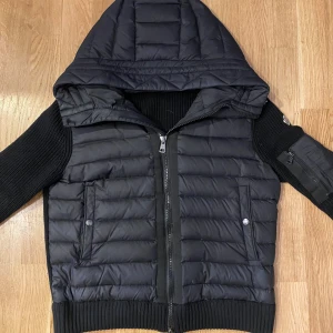 Moncler cardigan - Moncler cardigan med huva och dragkedja. Jackan e köpt i september 2024 från farfetch så ägt den i ett halv år och tagit bra hand om den. Storleken e M men aningen liten så kan passsa S också, tveka inte på o fråga vid funderingar!