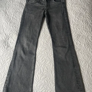 Grå jeans från Gina Tricot - Snygga grå jeans från Gina Tricot i storlek 152. De har utsvängda ben med knappar på fickorna baktill. Jeansen är i fint skick utan skavanker.