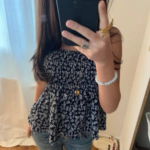 Blommig tubtopp i marinblå och vit - Säljer en söt blommig tubtopp i marinblå och vit. Toppen har en luftig passform och är perfekt för varma dagar. Den är prydd med små vita blommor som ger en romantisk touch.