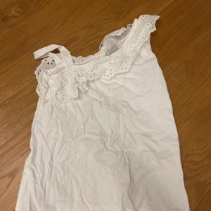 Vit blus från LC Waikiki - Söt vit blus från LC Waikiki med vackra spetsdetaljer och volang vid halsen. Perfekt för somriga dagar. Blusen är ärmlös och har en luftig passform. Storlek 140 men passar även xxs. Köpt från zalando.💕