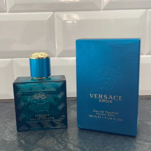 Versace Eros Eau de Toilette 50 ml - Säljer en flaska Versace Eros Eau de Toilette, 50 ml. Flaskan är i en elegant blå färg med guldiga detaljer och har en stilren design med Versaces ikoniska medusahuvud. Nästan full, Perfekt för den som vill ha en fräsch och maskulin doft.