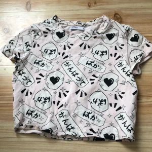 Rosa mönstrad t-shirt från Cropp - Säljer en cool rosa t-shirt från Cropp med svart och vitt grafiskt mönster. T-shirten har korta ärmar och en avslappnad passform. Perfekt för en unik och trendig stil!