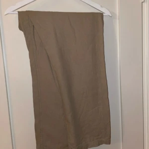 Beige byxor från H&M - Säljer ett par bekväma beige linne byxor från H&M i regular fit. Byxorna har elastisk midja med snörning för extra komfort. Perfekta för en avslappnad stil.