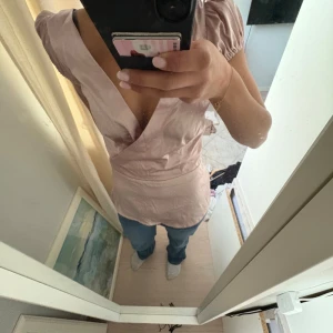 Rosa omlottopp från Zara - Säljer en elegant rosa omlottopp från Zara i satin. Toppen har korta puffärmar och en v-ringad design. Perfekt för att klä upp en outfit med lite extra stil men också skön att ha att sova i.💖