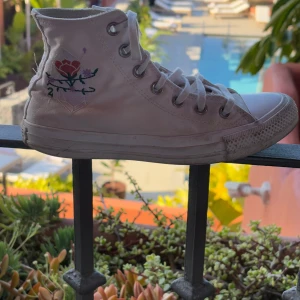 Ljusrosa Converse All Star sneakers - Säljer ett par ljusrosa Converse All Star sneakers med hög snörning och klassisk logga på sidan. Skorna har en unik broderad rosdetalj på sidan som ger dem en personlig touch. Perfekta för en avslappnad stil. Lite skitiga men fina.🫶🏻pris kan diskuteras.💸🗣️om du vill ha fler bilder är det bara att skicka en notis så svarar jag så fort jag kan.📸🎀💕
