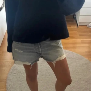 Grå jeansshorts från Zara - Säljer ett par grå jeansshorts från Zara. De har en avslappnad look med slitna detaljer och är perfekta för sommardagar. Shortsen har en klassisk femficksdesign och knappgylf.