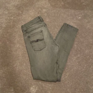 Grå jeans från Nudie Jeans - Snygga grå jeans från Nudie Jeans med en klassisk femficksdesign. De har en smal passform och är tillverkade i ett slitstarkt denimtyg. Perfekta för en stilren look.