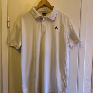 Vit pikétröja från Cross Sportswear - Säljer en stilren vit pikétröja från Cross Sportswear. Tröjan har en klassisk krage och knappar framtill. Perfekt för en avslappnad och sportig look.