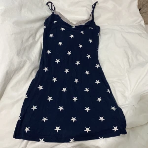 Mörkblå klänning med stjärnmönster - Säljer ett gulligt nattlinne med vita stjärnor och spetsdetaljer vid halsringningen. Klänningen har smala axelband och en bekväm passform. Lappen är borta men jag är S och tycker att den passar ganska bra, säljer pga ingen användning, mått finns i bilderna om man är osäker och tveka ej att skriva vid frågor🥰