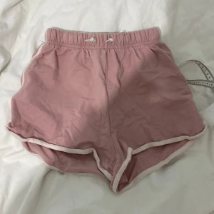 Rosa bomullsshorts från H&M - Säljer ett par mjuka och bekväma rosa shorts från H&M. De är tillverkade i 100% bomull och har en elastisk midja med snörning för justerbar passform. Perfekta för sommarn