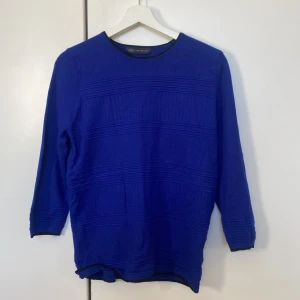 Blå tröja från M&S Collection - Snygg blå tröja från M&S Collection med trekvartsärm och ett subtilt mönster. Perfekt för en stilren look. Tröjan har en rund halsringning och är gjord i ett bekvämt material.