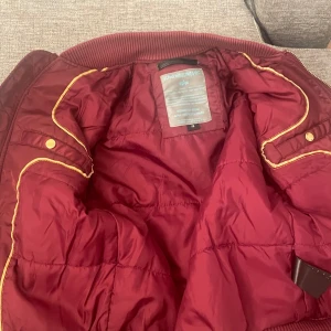 Vin röd ALPHA INDUSTRIES INC jacka  - Super fin vin röd jacka helt oanvänd på cirka 4-3 år och är i hyfsat fint skick 