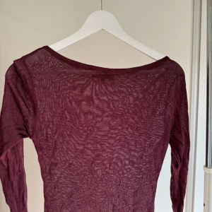Vinröd topp - Mycket bra sick. Bara använd några gånger. Toppen är vinröd och i genomskinligt material. Den är trekvartsärmad.