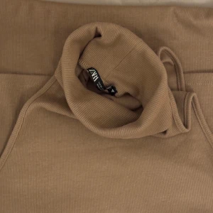 Beige ribbad klänning från Zara - Säljer en superfin brun klänning från Zara. Den är ribbad och har en tight passform, använd 1 gång. Storlek M 🤍