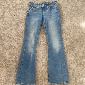 Blå bootcut jeans från Gina Tricot - Säljer ett par snygga blå bootcut och lowaist jeans från Gina Tricot i storlek 152. (passar mig som är 160) De har en snygg broderad detalj på bakfickorna.