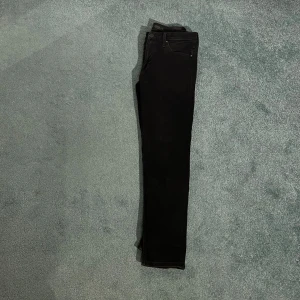 Svarta jeans - Säljer ett par svarta jeans i storlek 29/30. De har en klassisk design med fem fickor och en dragkedja. Perfekta för både vardag och fest!