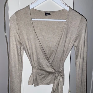 Wrap Top / Omlott Top - Säljer denna supersöta omlotta tröjan! Materialet är tunnt, färgen är beige och storlek XXS. Jag säljer den av anledning till att den ej passar och går ej att lämna tillbaka (väntade för länge). Ord. 329kr (tror jag), vid intresse hör gärna av dig 💕⭐️
