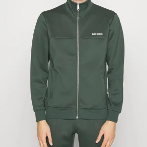 Les Deux Ballier Track - Helt ny dress köpt i butik för 2200, prislappen sitter tillomed kvar på byxorna. Säljer hela sättet för 1200 men pris går alltid att diskutera. Färgen är mörkgrön. Stl tröja: M Stl byxor: XL