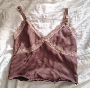Brun ribbad linnetopp från H&M Divided - Säljer en superfin brun ribbad linnetopp från H&M Divided. Den har spetsdetaljer och justerbara axelband. Perfekt för sommardagar eller som ett lager under en kofta. Toppen är i nyskick!