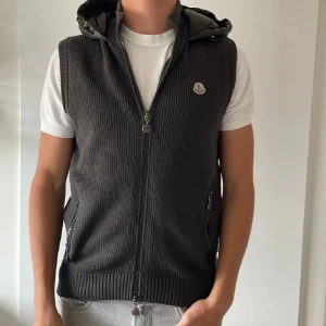 Grå stickad dunväst från Moncler - Säljer en snygg grå stickad dunväst från Moncler. Västen har en  quiltad baksida och en praktisk huva. passar M. Skick 9/10. Pris:3200🤝Pris kan diskuteras 👍