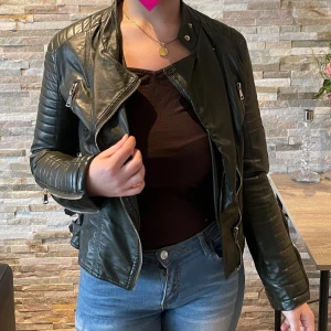 Grön skinnjacka  - En olivgrön skinnjacka i fint skick! Ger vintage vibes och passar så bra nu när det är mode med skinnjackor! Jackan har en fin passform i storlek S 