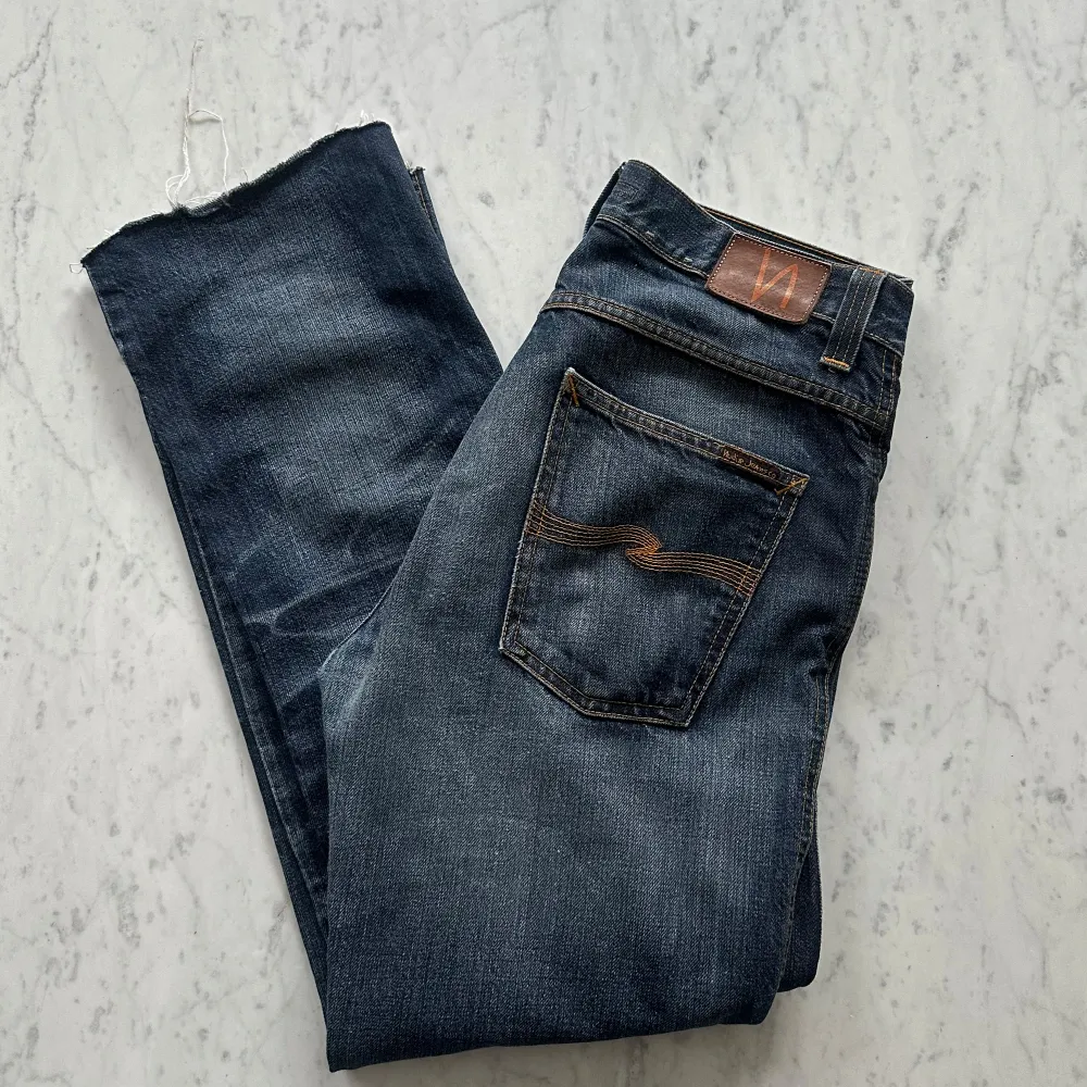 Ett par riktigt riktigt schyssta jeans från Nudie med coola slitningar .modellen Slim Jim . Lappen som visar storlek är avklippt men det är ungefär en 32 i W. Fint skick. nypris 1500kr, köp för endast 449.  Fast pris gäller🤝. Jeans & Byxor.