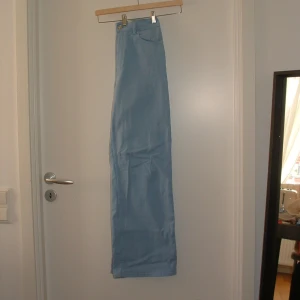 Ljusblå jeansbyxor - Säljer ett par ljusblå jeansbyxor i bra skick. De har en klassisk design med knapp och dragkedja framtill. Perfekta för en avslappnad stil och passar till de flesta tillfällen. Sköna och stilrena!