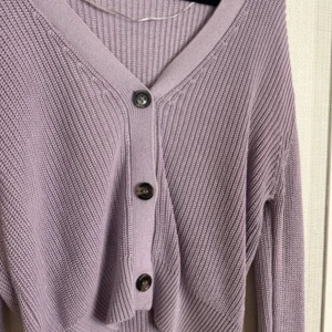 Ljuslila stickad kofta - Säljer en superfin ljuslila stickad kofta med knappar framtill. Den har en v-ringad design och långa ärmar, perfekt för både vår och höst. Koftan är i nyskick och passar perfekt till jeans eller kjol för en avslappnad look. 💜