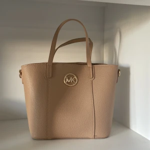 En snygg väska❣️ - Jag säljer min väska från märket MK och är beige,den är super fin till en snygg outfit!!pris kan diskuteras 