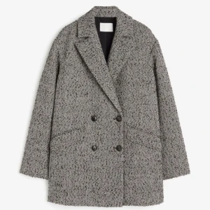 Grå kappa med fiskbensmönster - Säljer en snygg grå kappa med klassiskt fiskbensmönster. Den har en dubbelknäppt design med svarta knappar och stora fickor framtill. Perfekt för höst och vinter, och ger en stilren look. Kappan är långärmad och har en bekväm passform.