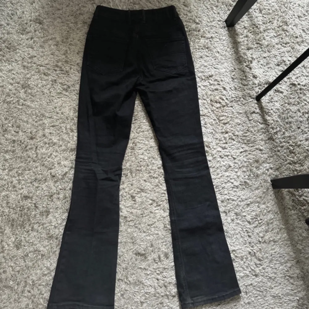 Svarta stretchiga bootcut jeans med hög midja, knappt använda inga tecken på användning passar storlek S - W28L32, hög midja Midja 34 cm Innerlår 81 cm Hela byxans längd ca 105 cm. Jeans & Byxor.