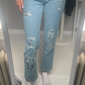Jeans med målning på - Blå jeans med hög midja, storlek 34. Använda någon enstaka gång så i fint skick. Är något korta på mig som är 177 cm. 