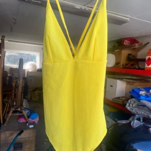 Gul body från BikBok - Säljer en superfin gul body från BikBok i storlek M. Den har en djup v-ringning och smala axelband som korsas i ryggen. Materialet är ribbat vilket ger en snygg textur och passformen är normal. Perfekt för sommarens alla äventyr! 🌞