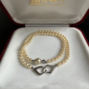 Pärlarmband från Majorica - Säljer ett elegant pärlhalsband från Majorica. Halsbandet har krämfärgade pärlor och ett stilrent silverfärgat lås med en dekorativ detalj. Perfekt för speciella tillfällen eller som en fin present. Kommer i en lyxig röd ask med certifikat!