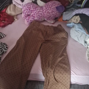 Bruna byxor med mönster från Free/Quent - Säljer ett par bruna byxor från Free/Quent i storlek small. De har ett coolt mönster med små svarta symboler över hela tyget. Byxorna ser ut att ha en loose passform och är perfekta för en avslappnad stil. De är i bra skick och redo för en ny ägare!