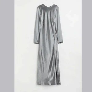 kläning - Säljer en ljusgrå satinklänning med hög slits fram👗 Aldrig använd. Klänningen har lång ärm med dragkedja vid ärmslut.