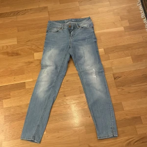 Ljusa jeans i slim fit - Säljer ett par ljusa jeans i slim fit. De har en klassisk femficksdesign och är perfekta för vardagsbruk. Jeansen har en snygg tvättad look med lite slitningar på låren för en avslappnad stil.