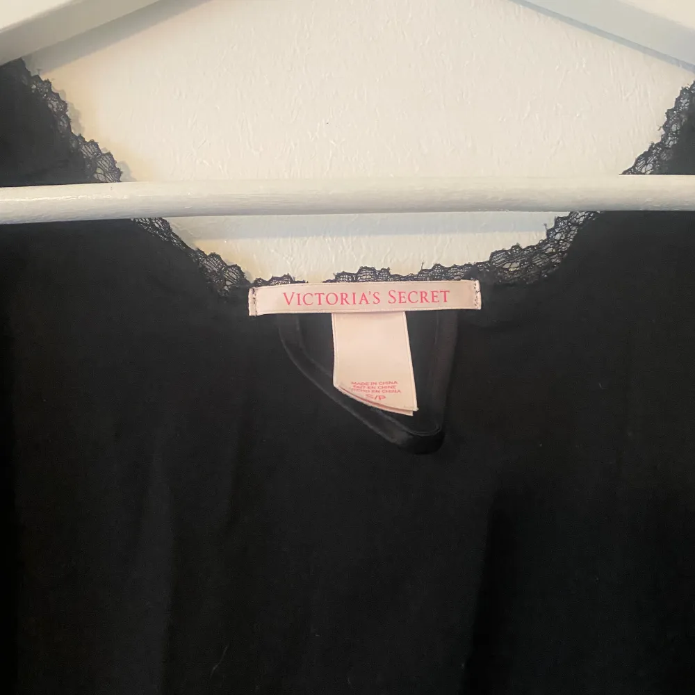 Säljer en elegant svart väst från Victoria's Secret. Den är gjord av 100% polyester och har en fin spetsdetalj runt halsen. Perfekt för att lägga till en touch av stil till vilken outfit som helst.. Övrigt.