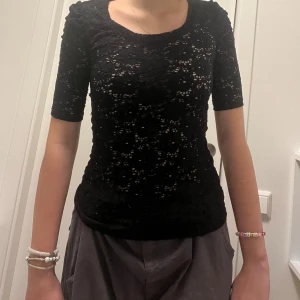 Svart topp/T-shirt med mönster  - Har använts typ 1 gång, håller bra, lite stickig, helst ha något under,
