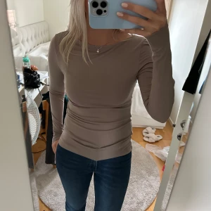 Beige långärmad topp - Säljer en superfin beige långärmad topp som sitter tight och är perfekt för både vardag och fest. Den är gjord i ett mjukt och stretchigt material som formar sig snyggt efter kroppen. Passar perfekt till jeans eller kjol!