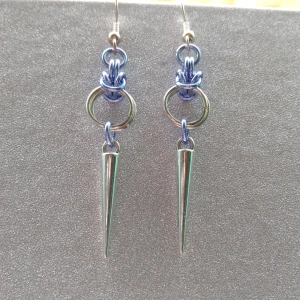 örhängen handgjorda  - Handgjorda örhängen gjorda i silverfärgade bindringar samt blå ringar och silverfärgade nitar. Mått ca 5.5cm långa. Öronkroken är nickelsäker 