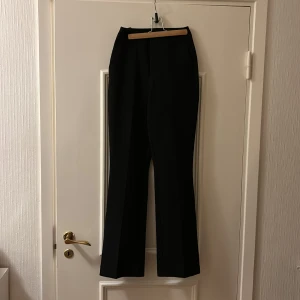 Svarta byxor från BikBok - Säljer ett par snygga svarta byxor från BikBok i storlek 34. De är gjorda av 92% polyester och 8% elastan, vilket gör dem både bekväma och stretchiga. Perfekta för både vardag och fest!