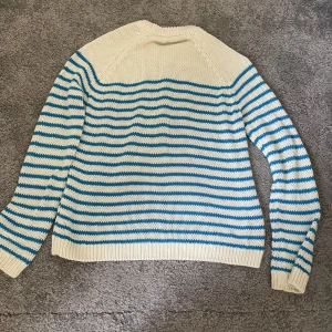 Randig stickad tröja från Zara - Säljer en superfin randig tröja från Zara i storlek S. Den är stickad och har ett snyggt mönster med vita och blå ränder. Perfekt för både vår och höst! Tröjan har långa ärmar och en bekväm passform. Perfekt för en casual look eller när du vill mysa till det lite extra. 💙🤍