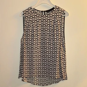 Mönstrad ärmlös topp från Zara - Säljer en snygg ärmlös topp från Zara i storlek S. Den har ett coolt svart och vitt mönster som verkligen sticker ut. Perfekt för både vardag och fest! Toppen är i ett lätt och bekvämt material, vilket gör den idealisk för varmare dagar.