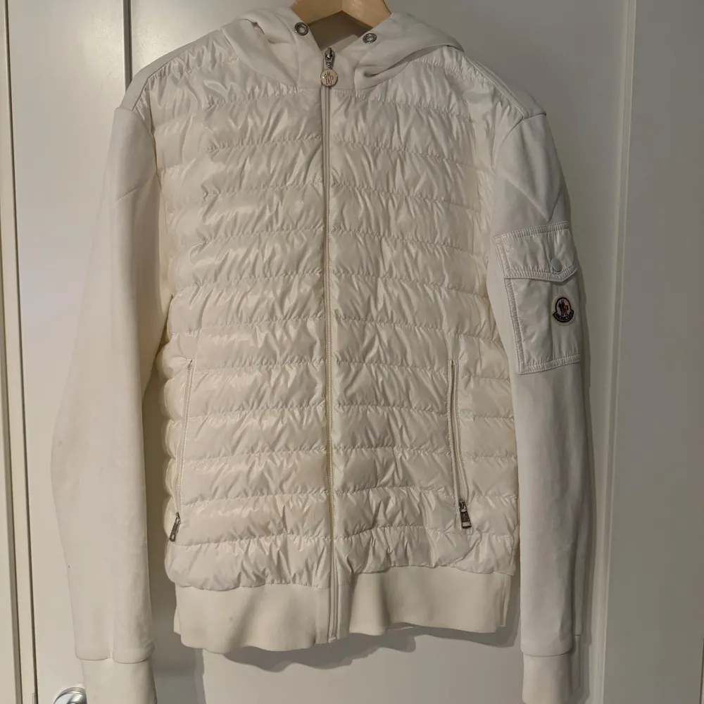 En vit moncler cardigan i väldigt bra skick. Finns 2-3 små smuts fläckar som tyvärr ej går bort. Har kemtvättat den men de går ej bort. Den är i storlek medium. Scannade qr koden och skrev in koden på monclers hemsida. Den är köpt ifrån garmsmarket.. Jackor.