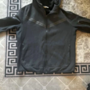 Svart fleecejacka med dragkedja - Säljer en svart fleecejacka som är perfekt för kyliga dagar. Den har en dragkedja framtill och långa ärmar. Jackan är i bra skick och passar både till vardags och utomhusaktiviteter.