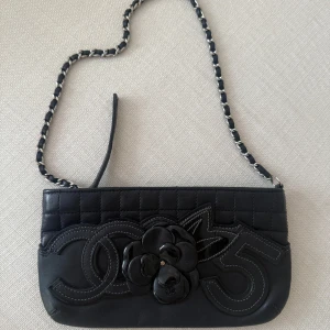 Vintage Chanel mini pochette Camellia NO. 5 2005-2006 Lambskin - Rare vintage Chanel mini bag in lambskin. The exterior features a playful embossed design combining matte and patent leather, showing iconic Chanel symbols: the interlocking C, the camellia flower, and the number 5. Beneath this embellishment is a di