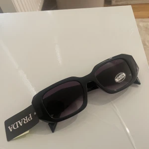 Prada  - Prada solglasögon, rektangulär form med guld logga.  Aldrig använda  Kopi.